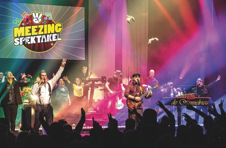 Optreden van Het Meezingspektakel met muzikanten en publiek in theaterlicht